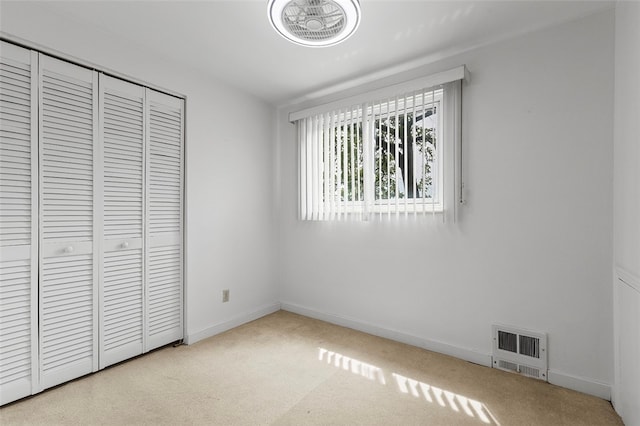 unfurnished bedroom featuring light carpet and a closet