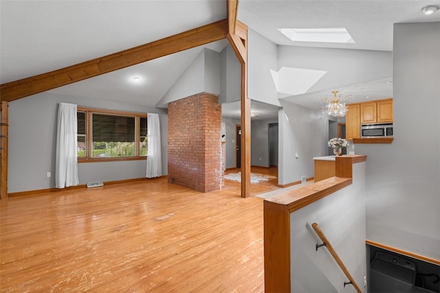 unfurnished living room featuring an inviting chandelier, light hardwood / wood-style flooring, and lofted ceiling with skylight