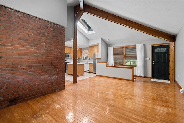 unfurnished living room with a skylight, high vaulted ceiling, light hardwood / wood-style floors, brick wall, and beamed ceiling