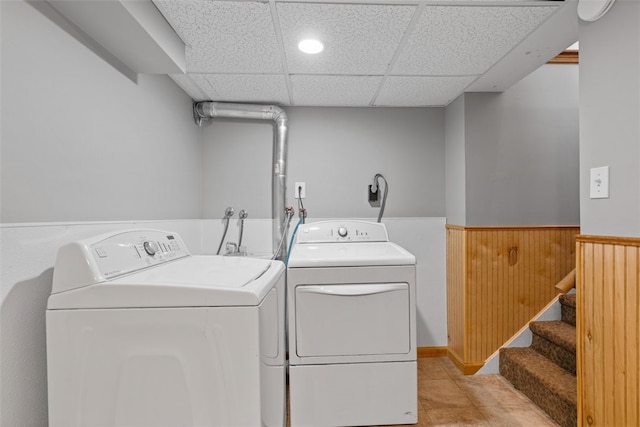 laundry area featuring separate washer and dryer, wooden walls, and light tile patterned flooring