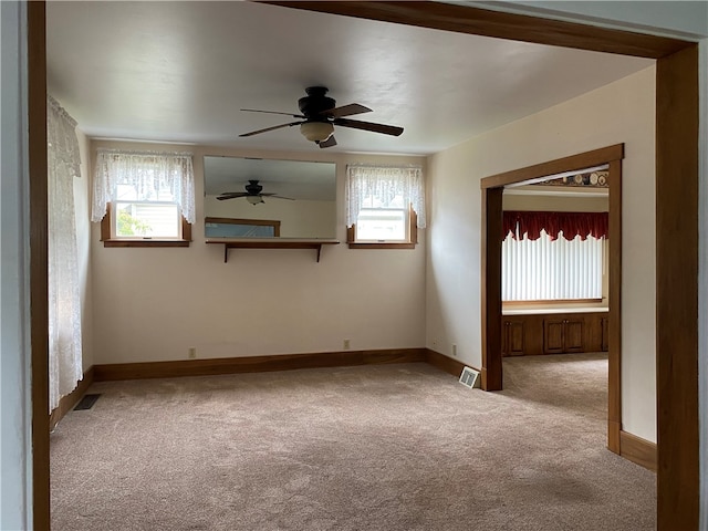 carpeted empty room with ceiling fan and a wealth of natural light