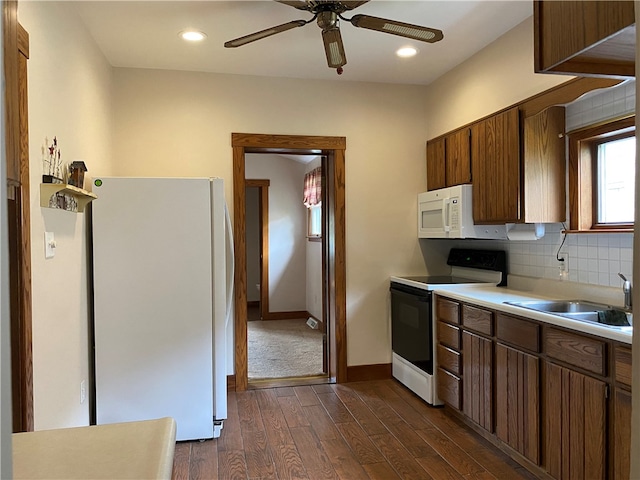 kitchen with dark wood-type flooring, sink, backsplash, white appliances, and ceiling fan