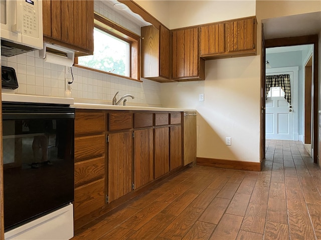 kitchen featuring sink, black range, backsplash, and dark wood-type flooring