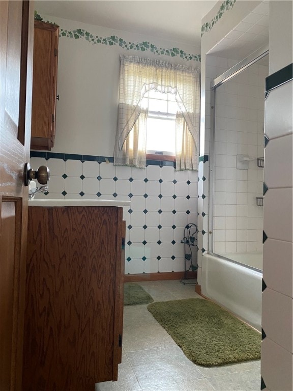 bathroom with tile walls and combined bath / shower with glass door