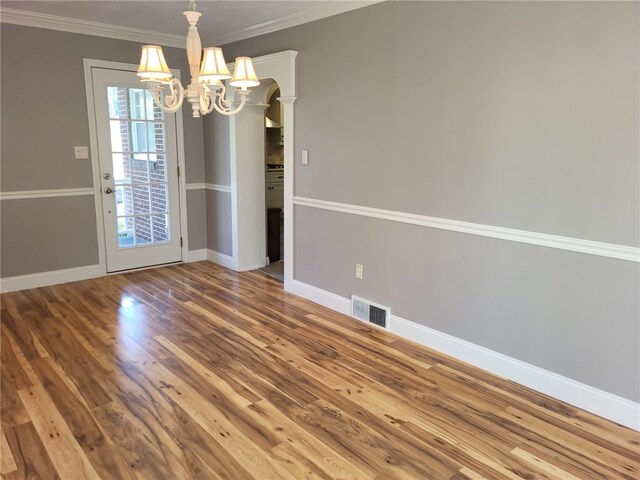 unfurnished dining area featuring crown molding, an inviting chandelier, and hardwood / wood-style flooring