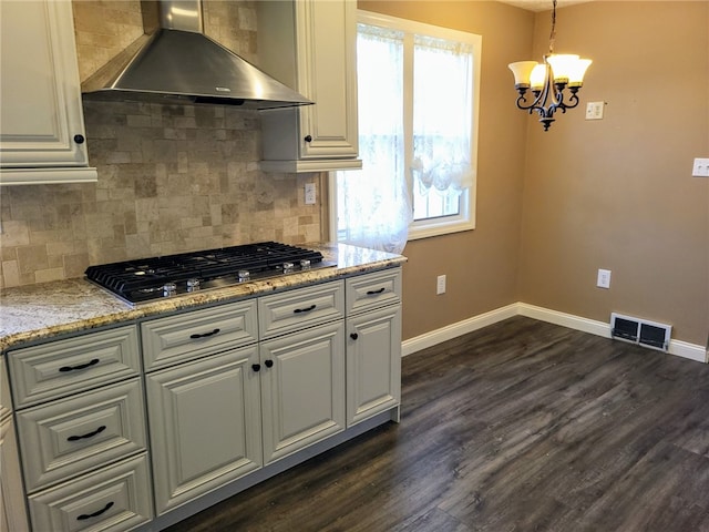 kitchen with decorative light fixtures, dark wood-type flooring, wall chimney exhaust hood, tasteful backsplash, and stainless steel gas cooktop