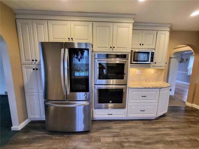 kitchen featuring appliances with stainless steel finishes, white cabinetry, tasteful backsplash, light stone counters, and dark hardwood / wood-style flooring