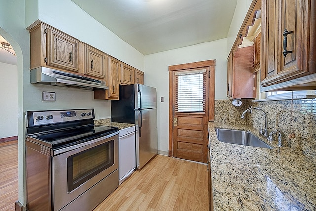 kitchen with sink, custom range hood, appliances with stainless steel finishes, light hardwood / wood-style flooring, and light stone countertops