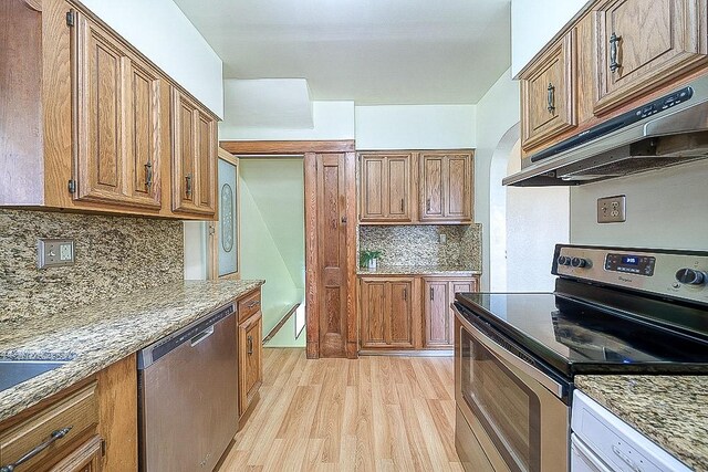 kitchen featuring backsplash, light hardwood / wood-style flooring, appliances with stainless steel finishes, and light stone countertops