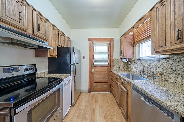 kitchen featuring tasteful backsplash, light hardwood / wood-style floors, light stone countertops, sink, and stainless steel appliances