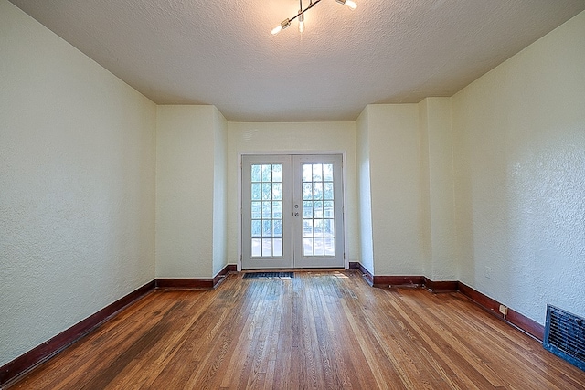 spare room with a textured ceiling, french doors, and hardwood / wood-style floors