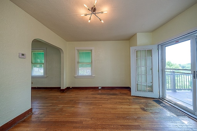 spare room featuring a textured ceiling, an inviting chandelier, and wood-type flooring