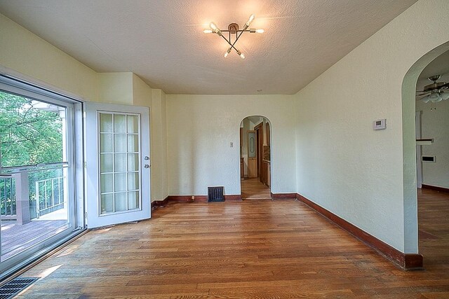 empty room with a textured ceiling, ceiling fan, and hardwood / wood-style floors