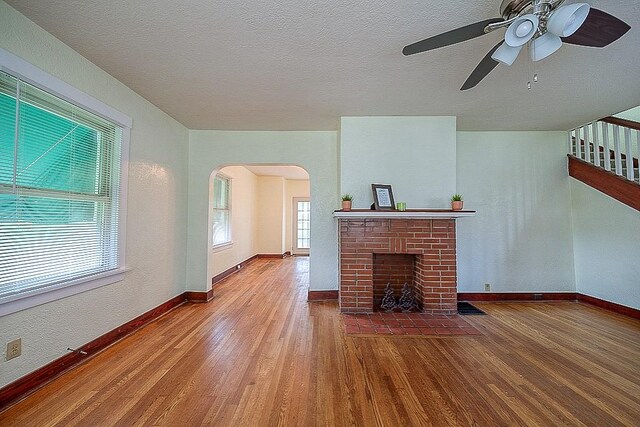 unfurnished living room featuring a fireplace, ceiling fan, and wood-type flooring