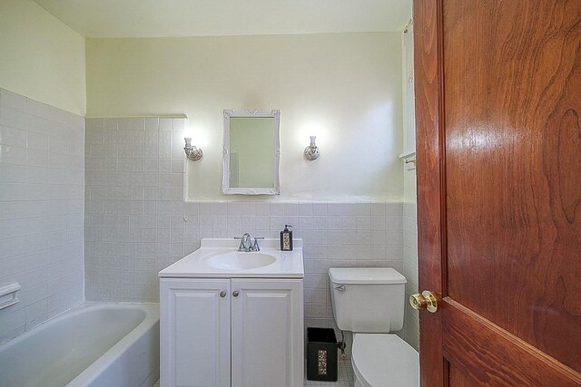 full bathroom with tile walls, vanity, bathing tub / shower combination, and toilet