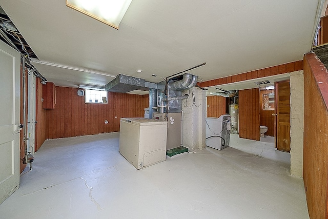 basement featuring gas water heater and wood walls