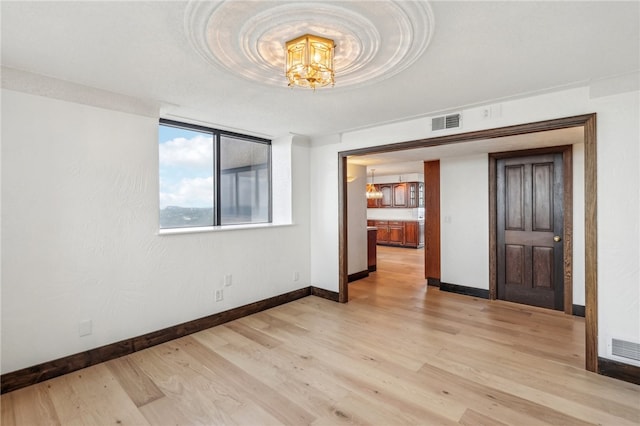 spare room featuring light hardwood / wood-style flooring and an inviting chandelier