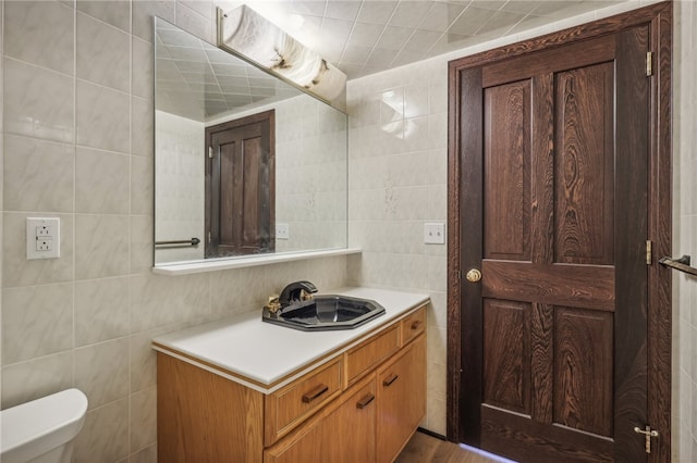 bathroom with vanity, tile walls, hardwood / wood-style floors, and toilet