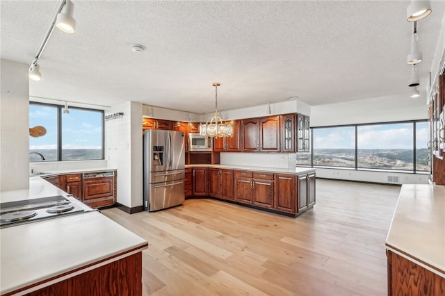 kitchen featuring pendant lighting, an inviting chandelier, light wood-type flooring, appliances with stainless steel finishes, and a textured ceiling