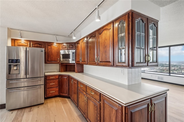 kitchen featuring track lighting, appliances with stainless steel finishes, a textured ceiling, and light wood-type flooring