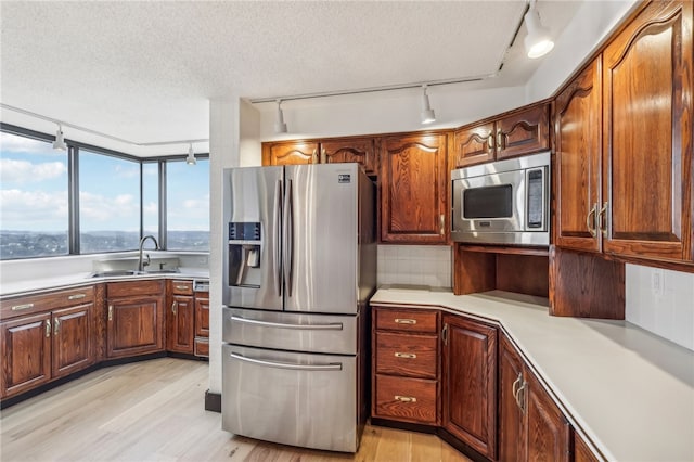 kitchen featuring light hardwood / wood-style flooring, a textured ceiling, appliances with stainless steel finishes, and sink