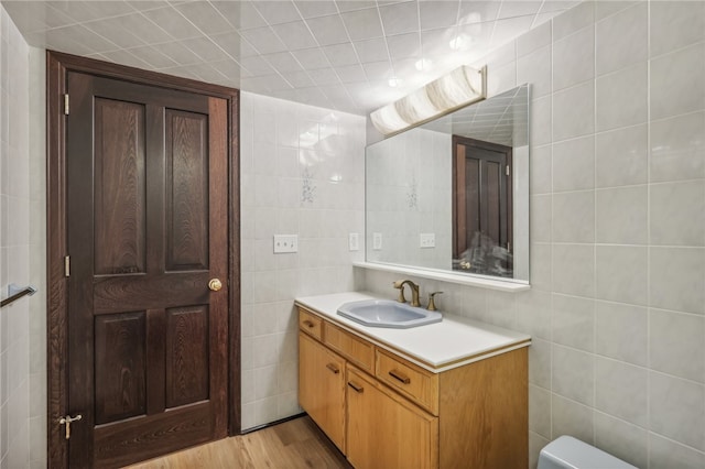 bathroom featuring vanity, toilet, hardwood / wood-style flooring, and tile walls