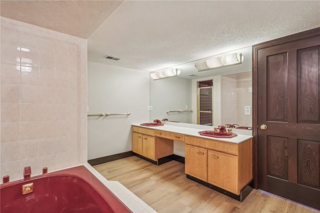 bathroom with vanity, hardwood / wood-style flooring, a textured ceiling, and a bath