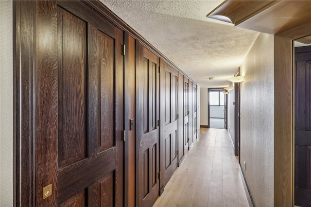 corridor featuring light hardwood / wood-style flooring and a textured ceiling