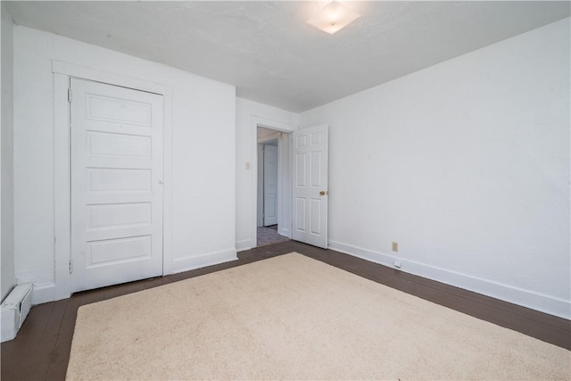 unfurnished bedroom featuring dark wood-type flooring and baseboards