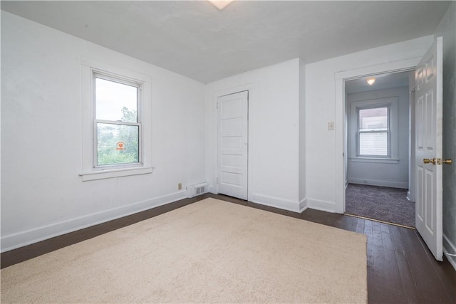 unfurnished bedroom with visible vents, baseboards, and dark wood-style floors