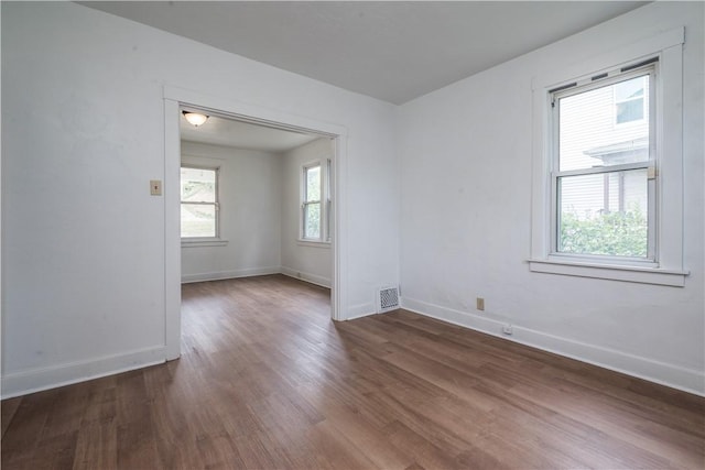 empty room featuring baseboards, plenty of natural light, and wood finished floors