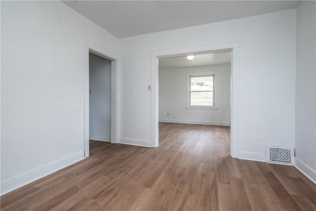 unfurnished room with visible vents, baseboards, and wood finished floors