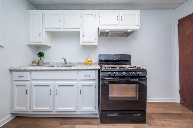 kitchen with range hood, gas stove, white cabinetry, and a sink