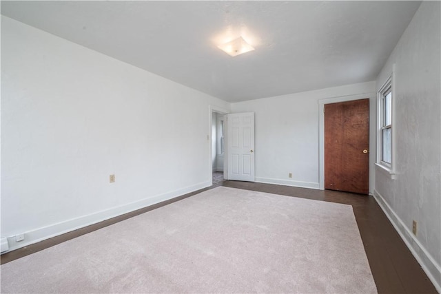 spare room with dark wood-type flooring and baseboards