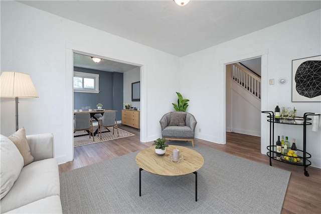 living room featuring stairway, baseboards, and wood finished floors