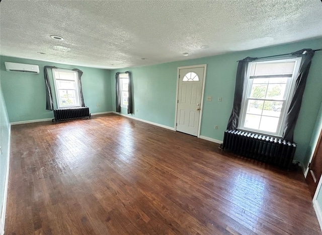 foyer entrance with a wealth of natural light, wood-type flooring, a textured ceiling, and radiator heating unit