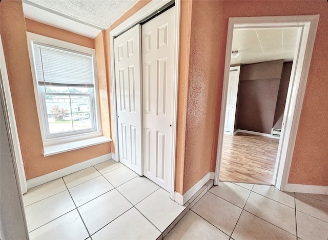 unfurnished bedroom featuring light tile patterned flooring, a textured ceiling, and a closet