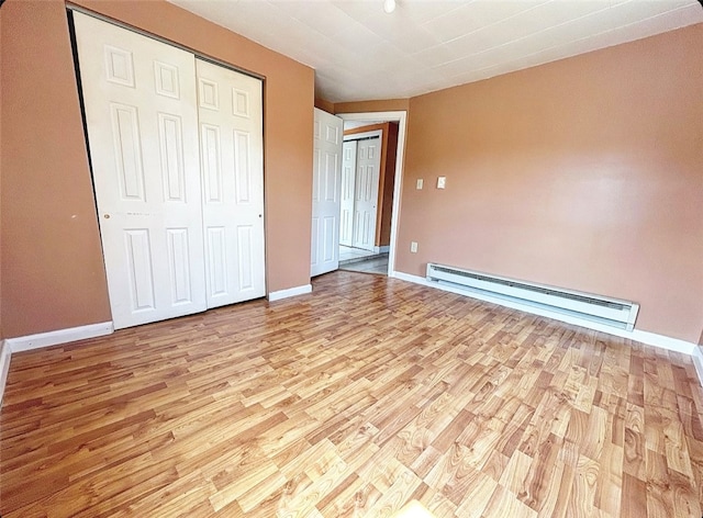 unfurnished bedroom featuring light wood-type flooring and baseboard heating