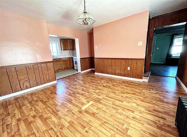 empty room with an inviting chandelier and light hardwood / wood-style flooring