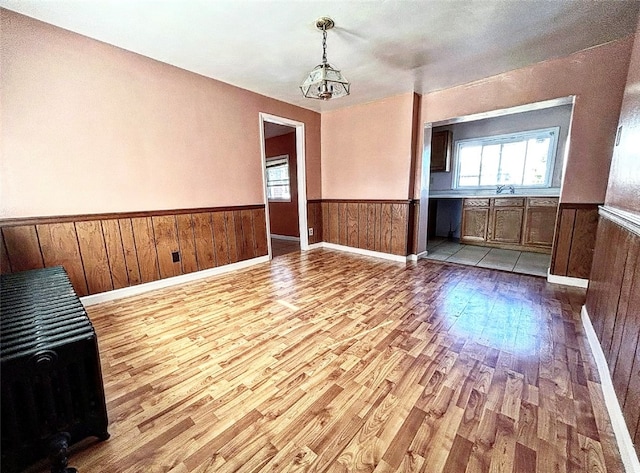 unfurnished room featuring light wood-type flooring, sink, and an inviting chandelier