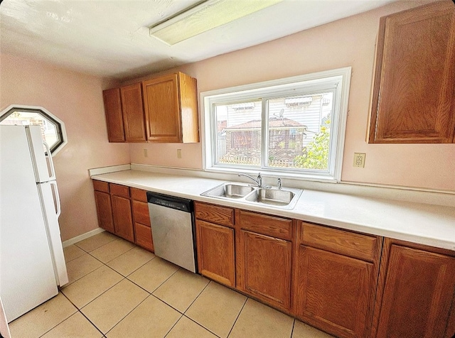 kitchen with light tile patterned flooring, stainless steel dishwasher, sink, and white fridge