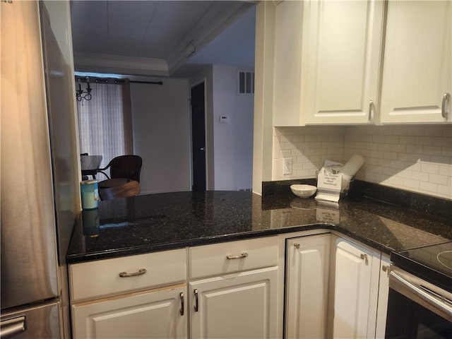 kitchen with stainless steel fridge, white cabinetry, crown molding, and dark stone countertops