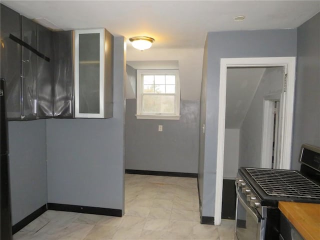 kitchen with glass insert cabinets, gas stove, wooden counters, and baseboards