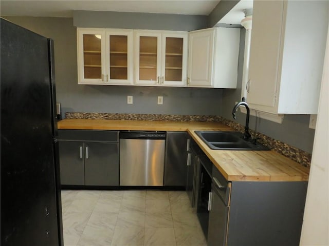 kitchen featuring dishwasher, butcher block countertops, freestanding refrigerator, white cabinetry, and a sink