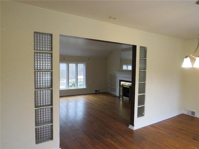 unfurnished living room with a fireplace, wood finished floors, visible vents, and baseboards