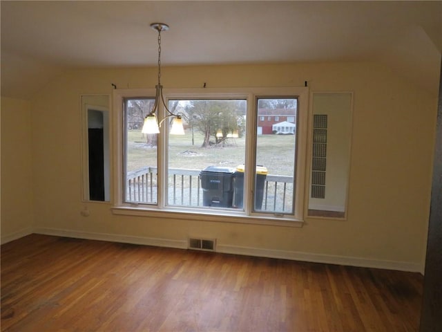 unfurnished dining area with visible vents, vaulted ceiling, baseboards, and wood finished floors