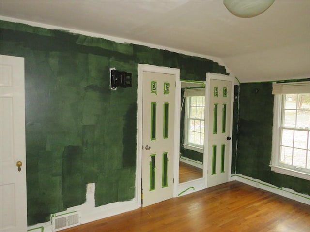 spare room featuring lofted ceiling, visible vents, and wood finished floors