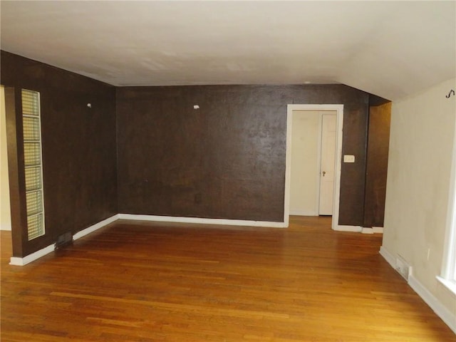 spare room featuring lofted ceiling, wood finished floors, and baseboards