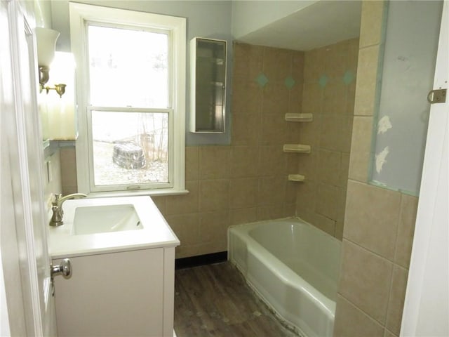 bathroom with bathing tub / shower combination, tile walls, vanity, and wood finished floors