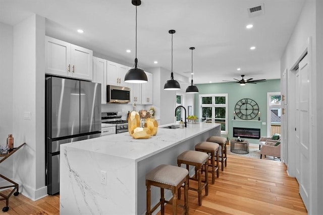 kitchen featuring sink, white cabinetry, a kitchen breakfast bar, stainless steel appliances, and a kitchen island with sink